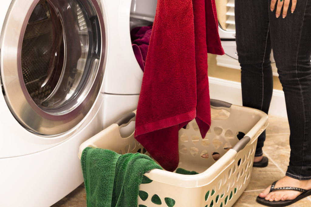 Domestic Life: Woman removing towels from clothes dryer to Laundry basket